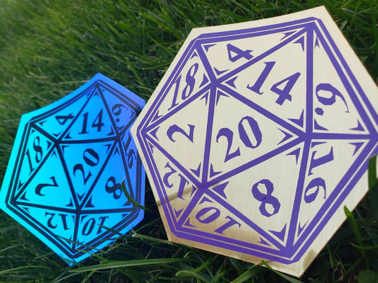 Two vibrant vinyl decals in the shape of D20 dice, one in blue and one in gold, featuring detailed numbers for tabletop RPG enthusiasts. Placed on grass, these hexagonal decals are perfect for Dungeons & Dragons fans and role-playing game accessories.